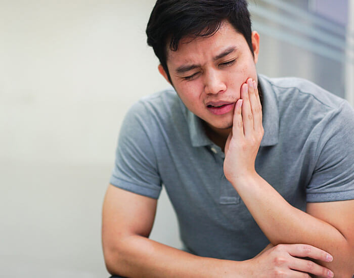 man holding mouth in pain